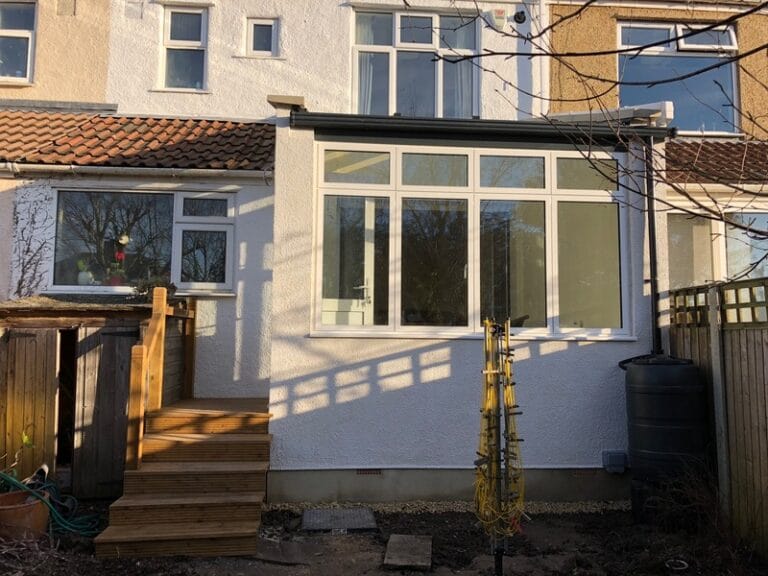 Rear house extension finished in Bristol, with a wide glass window overlooking the garden.